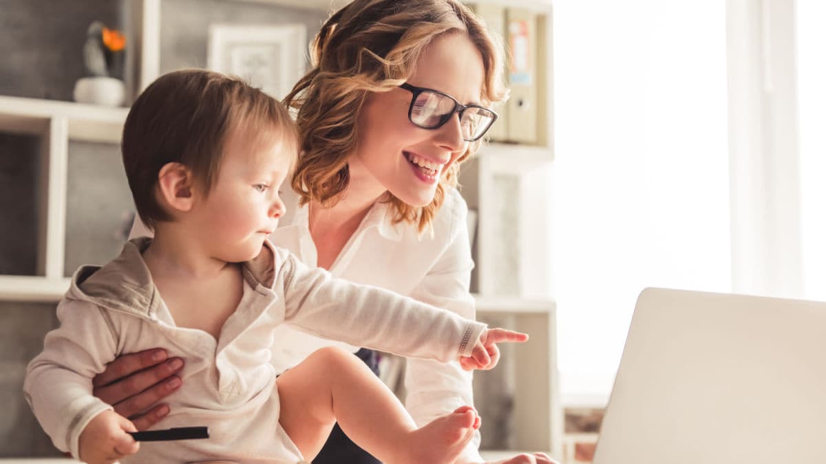 Mamma lavora al pc, in smart working, con in braccio il suo bimbo
