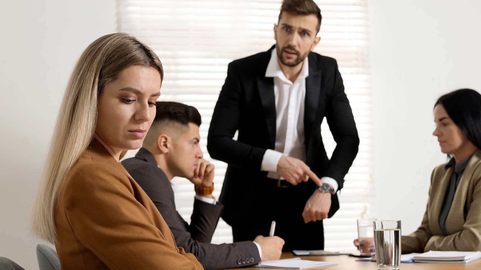 Donna al tavolo con colleghi vittima di straining sul lavoro