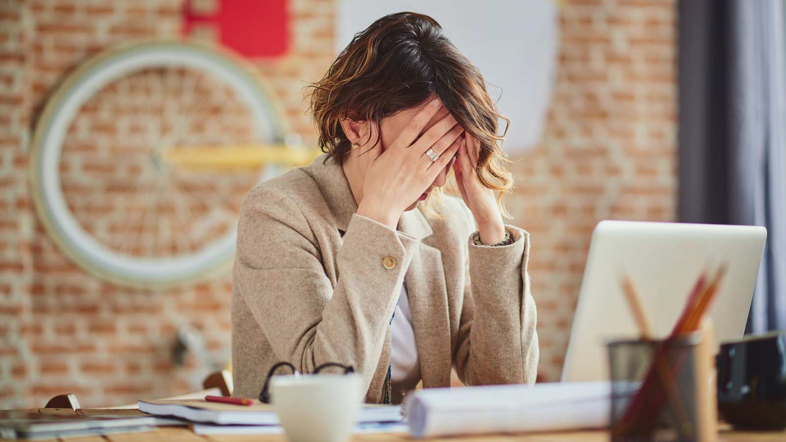 Donna con le mani sul volto perché soffre di una delle malattie invisibili al lavoro