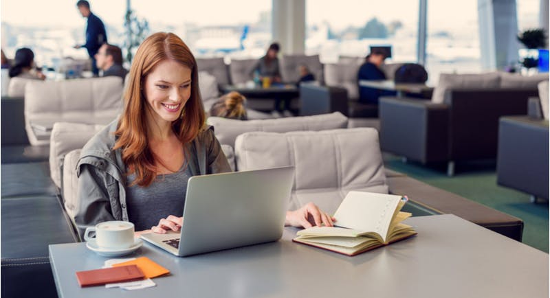 Giovane donna lavora con il computer portatile in aeroporto