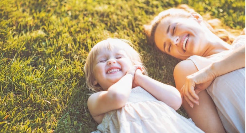 mamma e figlia sorridenti distese sull'erba