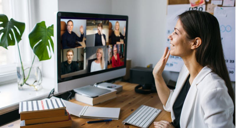 donna lavora al computer in smart working e saluta i colleghi in videochiamata