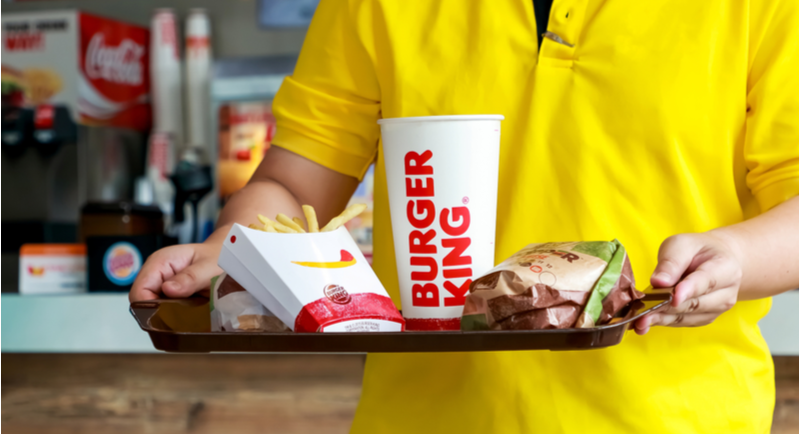 Un cliente torna al proprio tavolo con un vassoio contenente un menu di Burger King