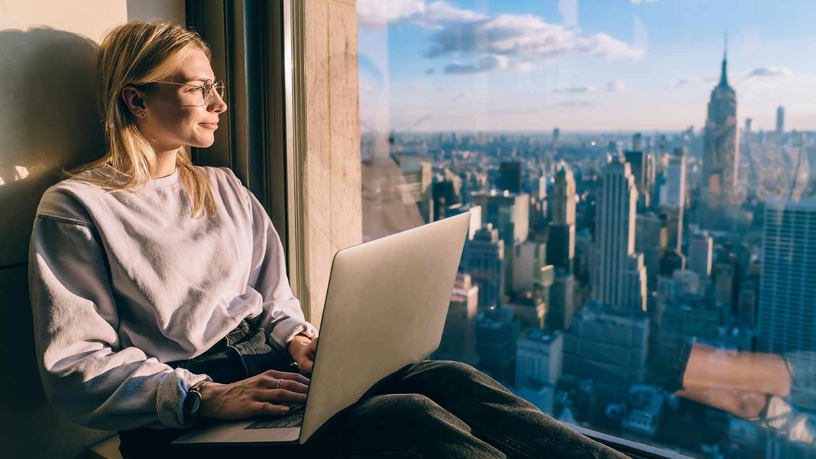 nomadi digitali: una giovane lavora da un palazzo con vista su Manhattan