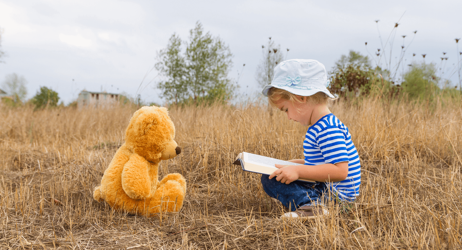 img 1: “Bimba legge un libro, seduta di fronte al suo orsacchiotto”