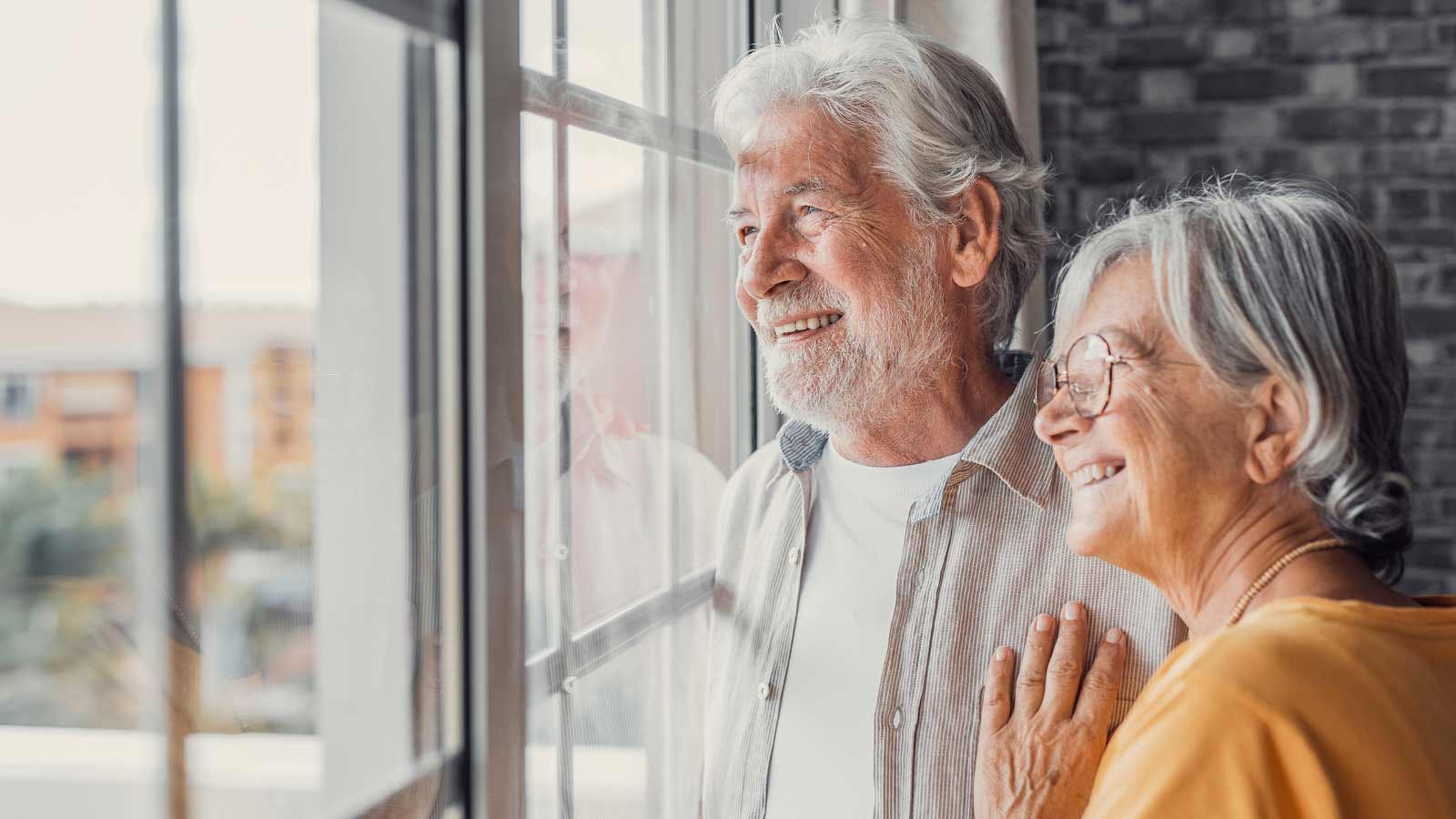 Assegno di inclusione: una signora e un signore over 60 guardano fuori dalla finestra