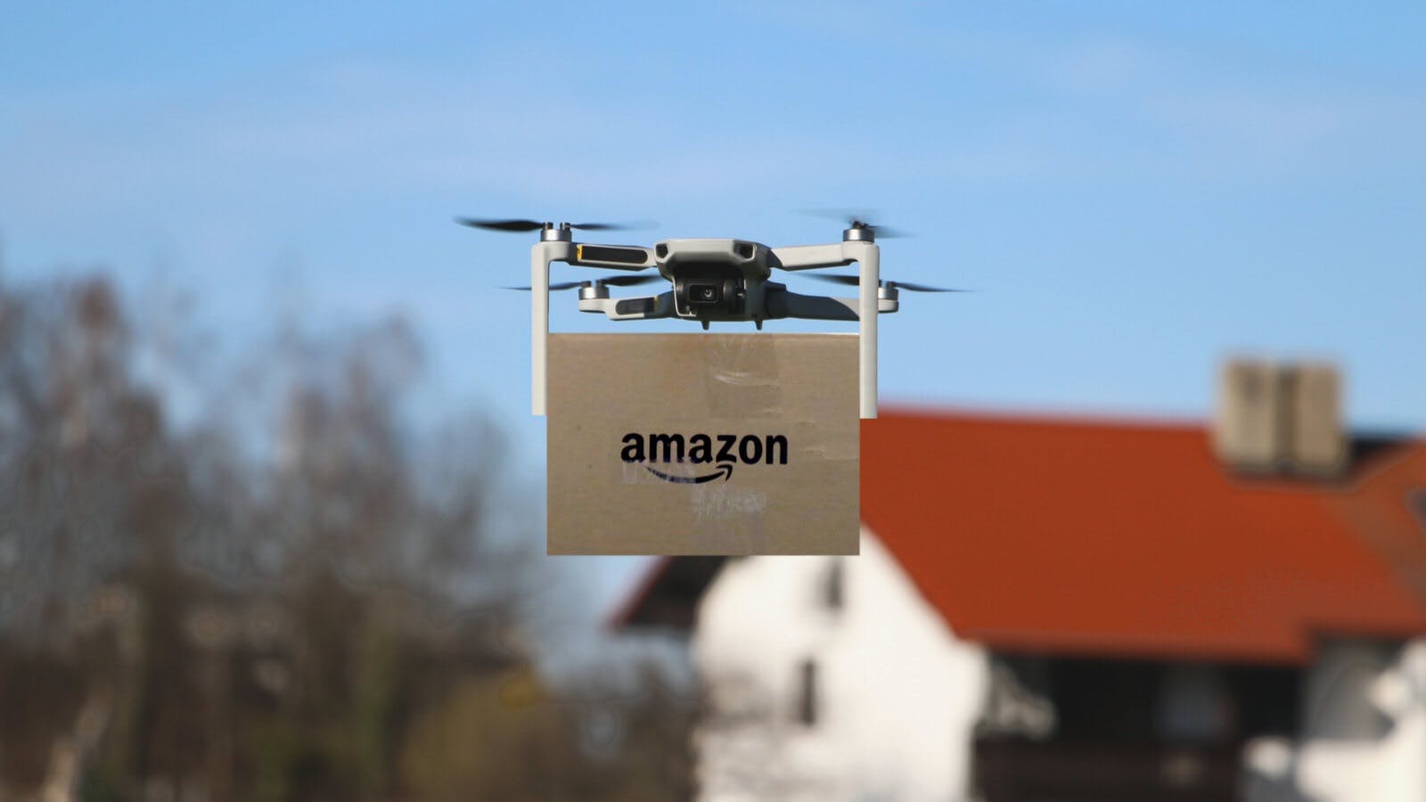 img 1: “Un drone effettua la consegna a domicilio di un pacco Amazon”