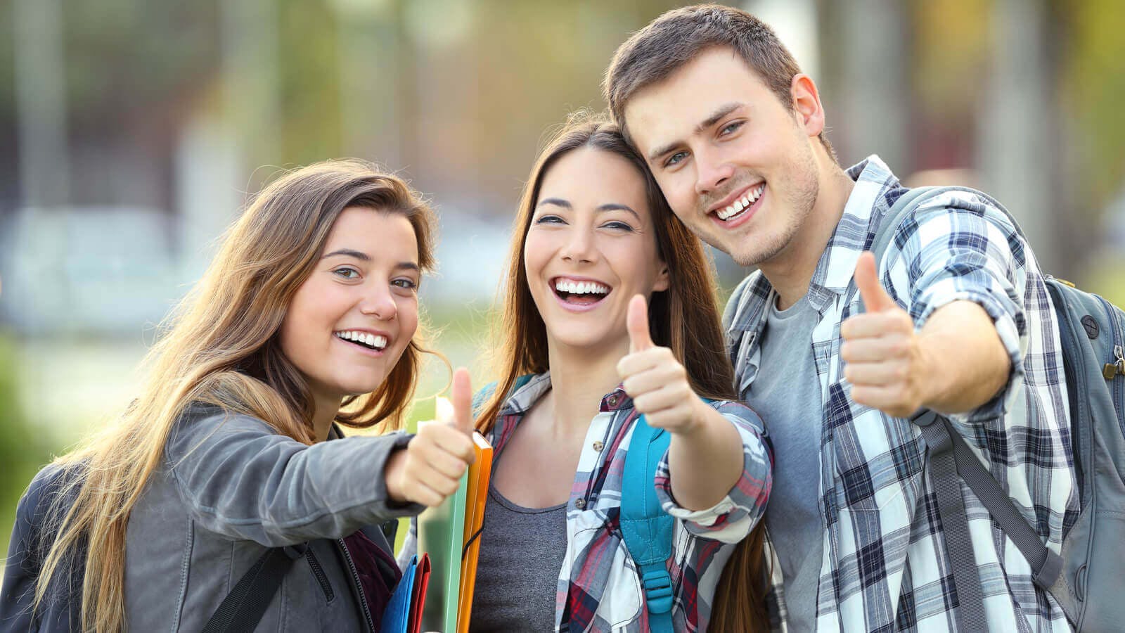 Tre giovani studenti, sorridono lungo il vialetto del campus
