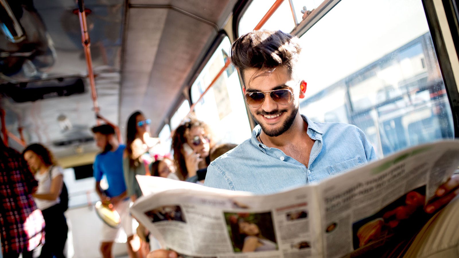 Uomo legge un quotidiano, in autobus